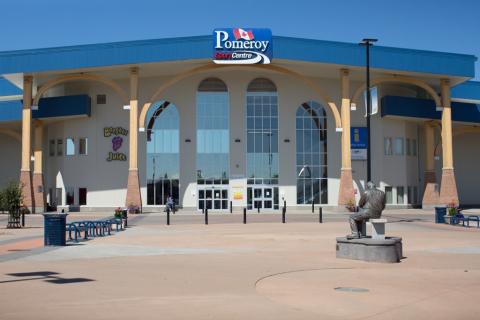 Exterior of Pomeroy Sport Centre. There is a large glass door entrances and a statue facing the arena.