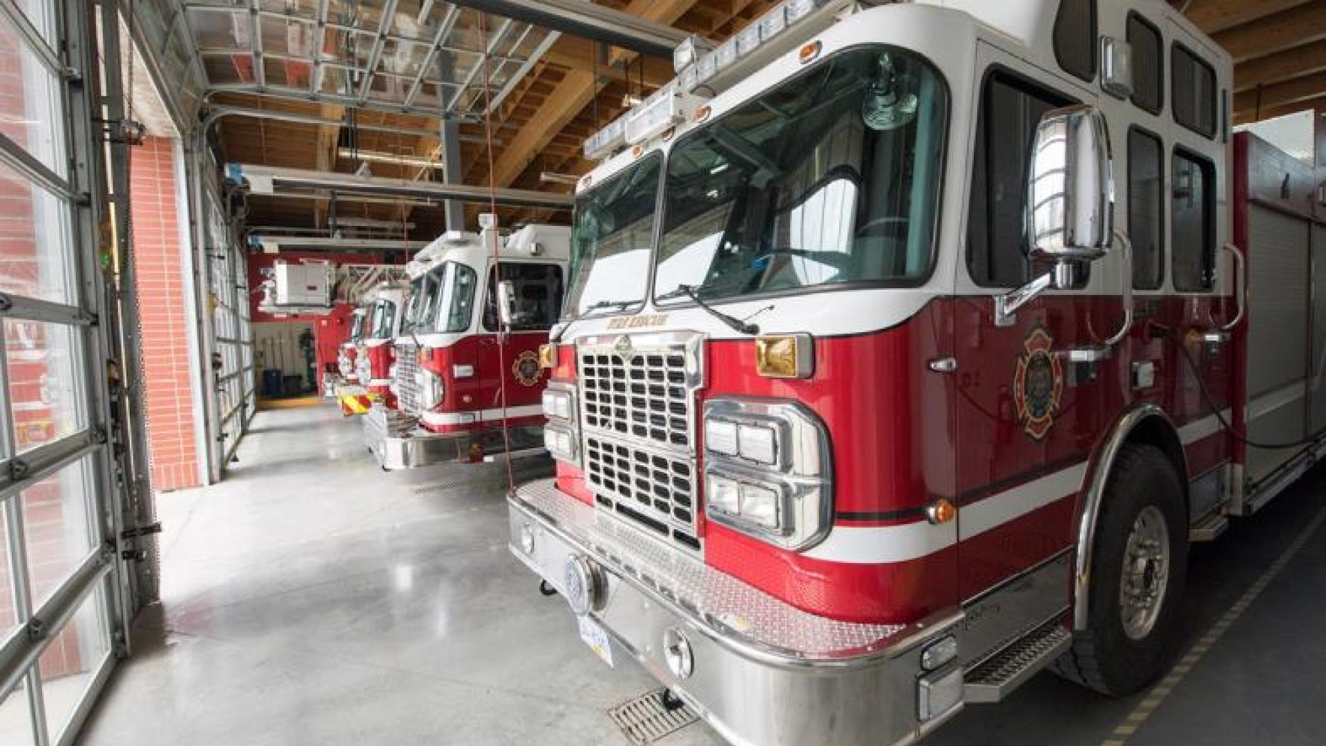 Red firetrucks parked inside a garage.