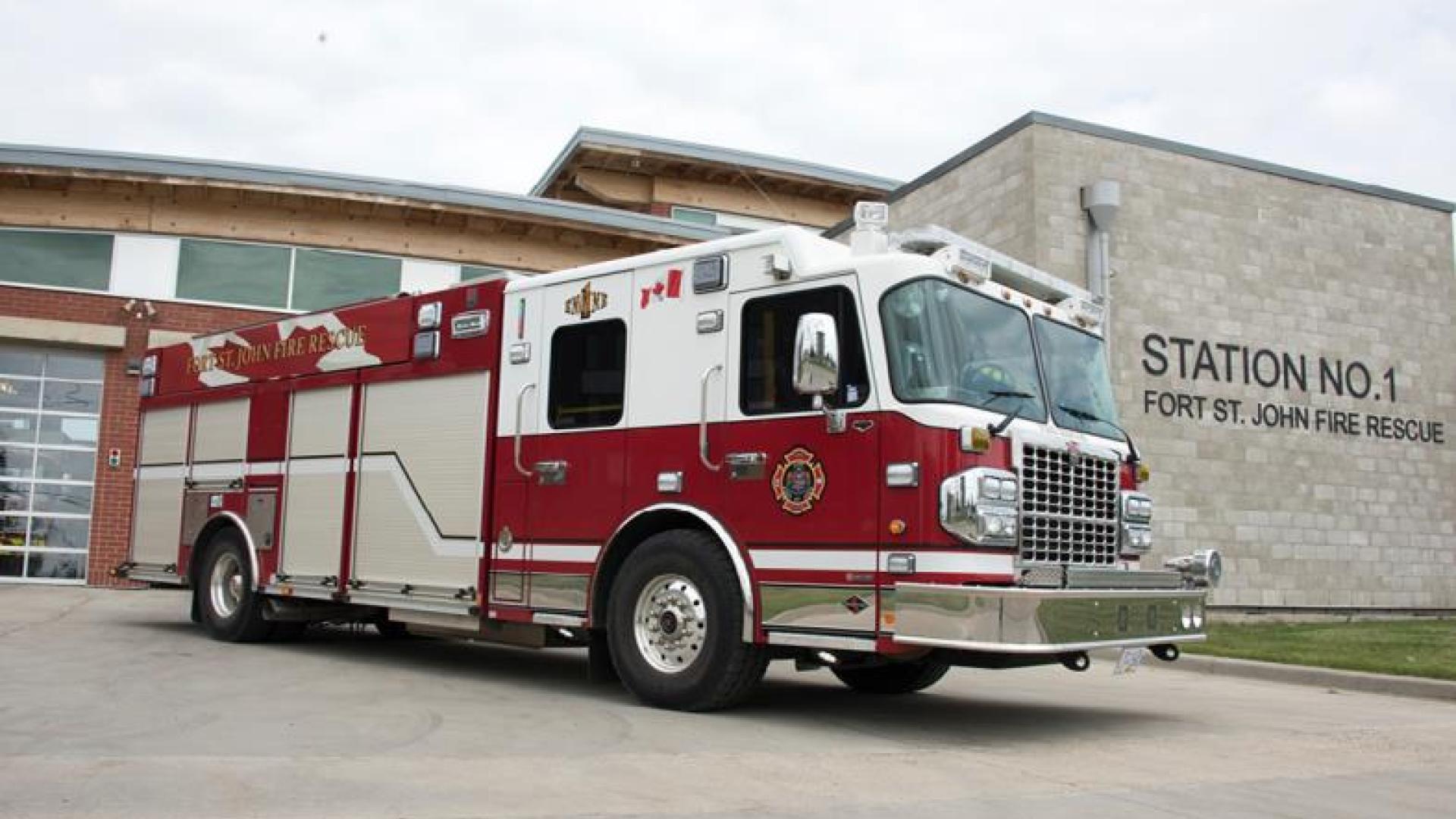 Red firetruck parked outside of fire station.