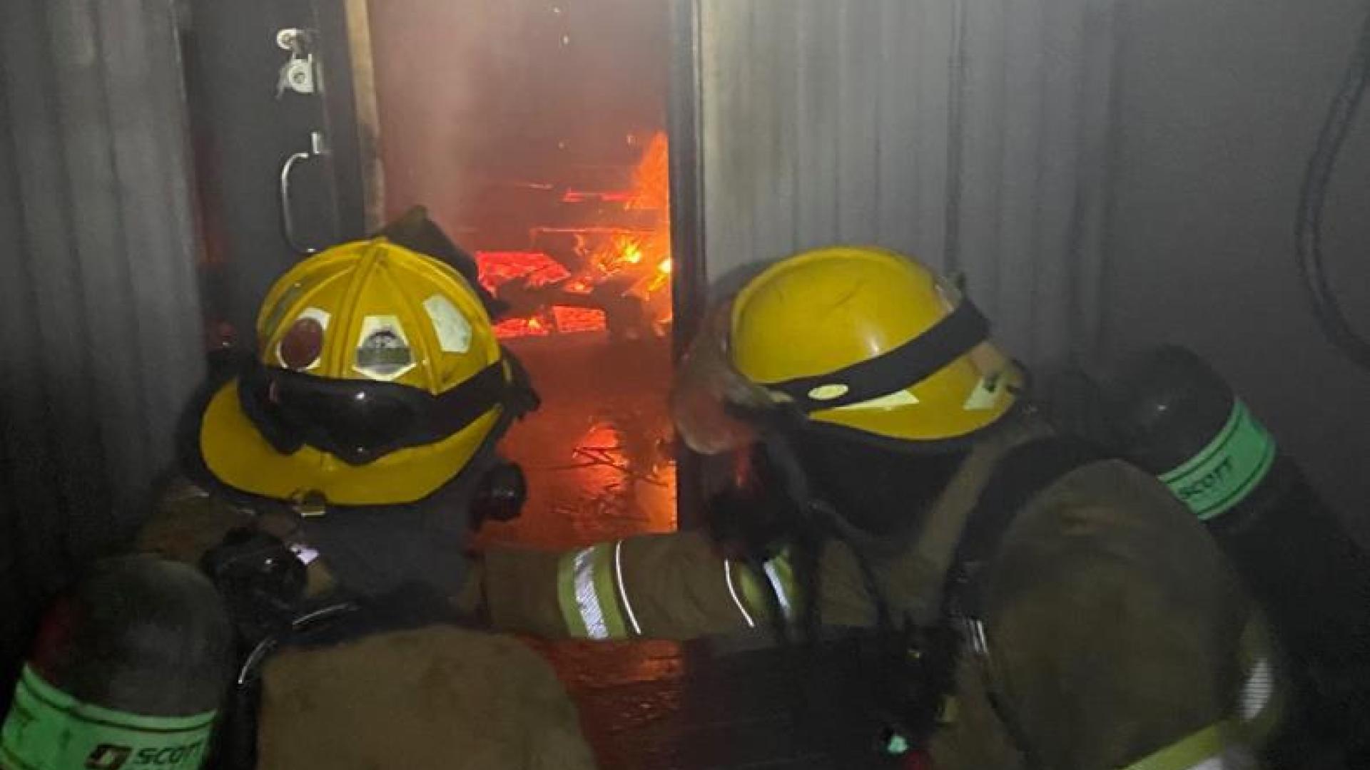 Two firefighters practice fire suppression from the interior.