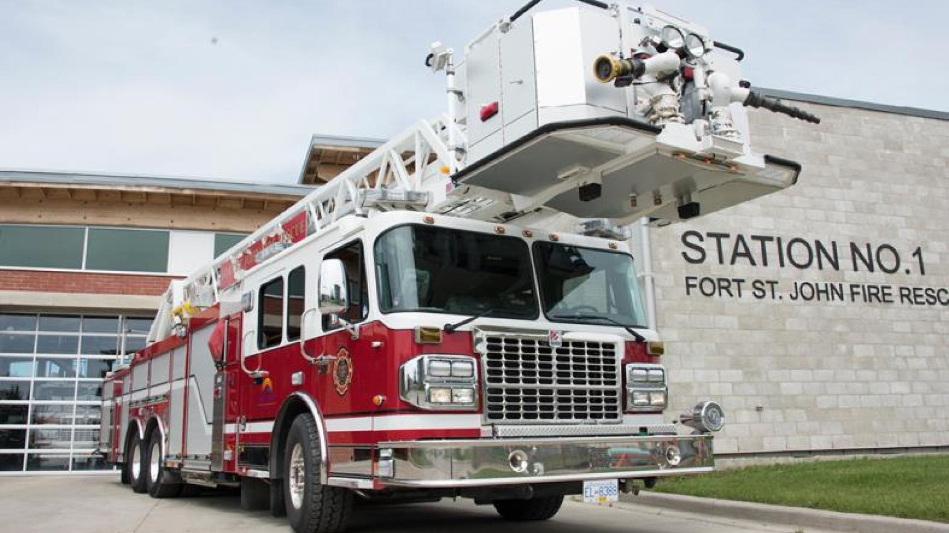 Red firetruck parked outside of fire station.