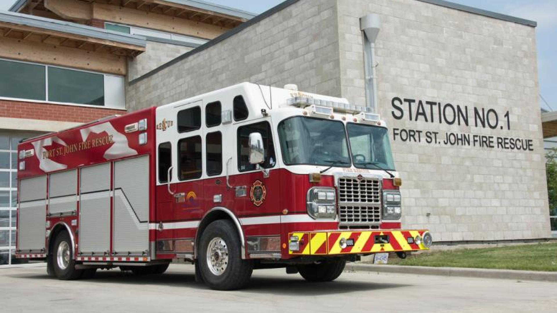 Red firetruck parked outside of fire station.