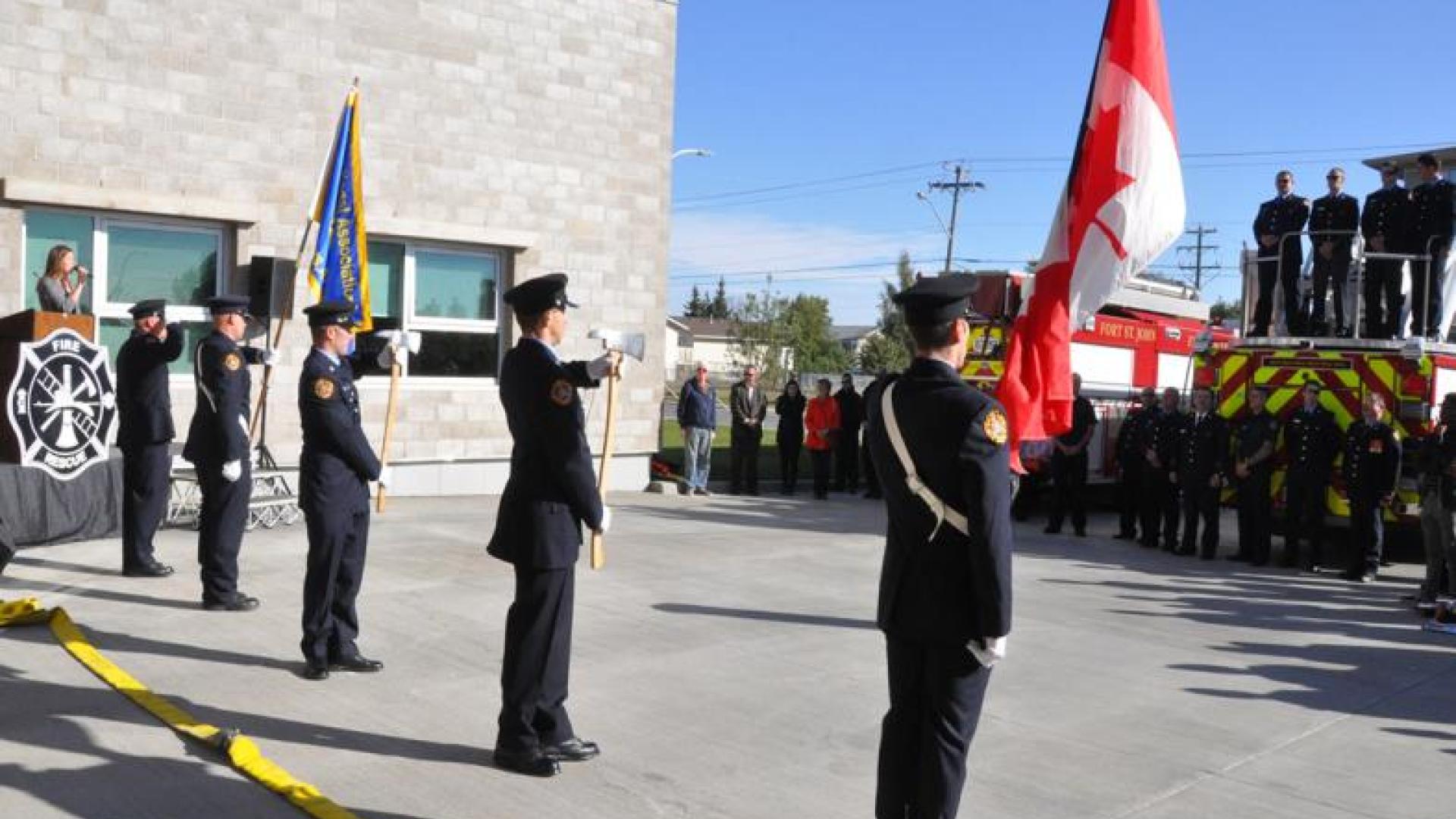 Firefighters standind in attention during fire station opening ceremony. They are dressed in ceremonial uniforms.