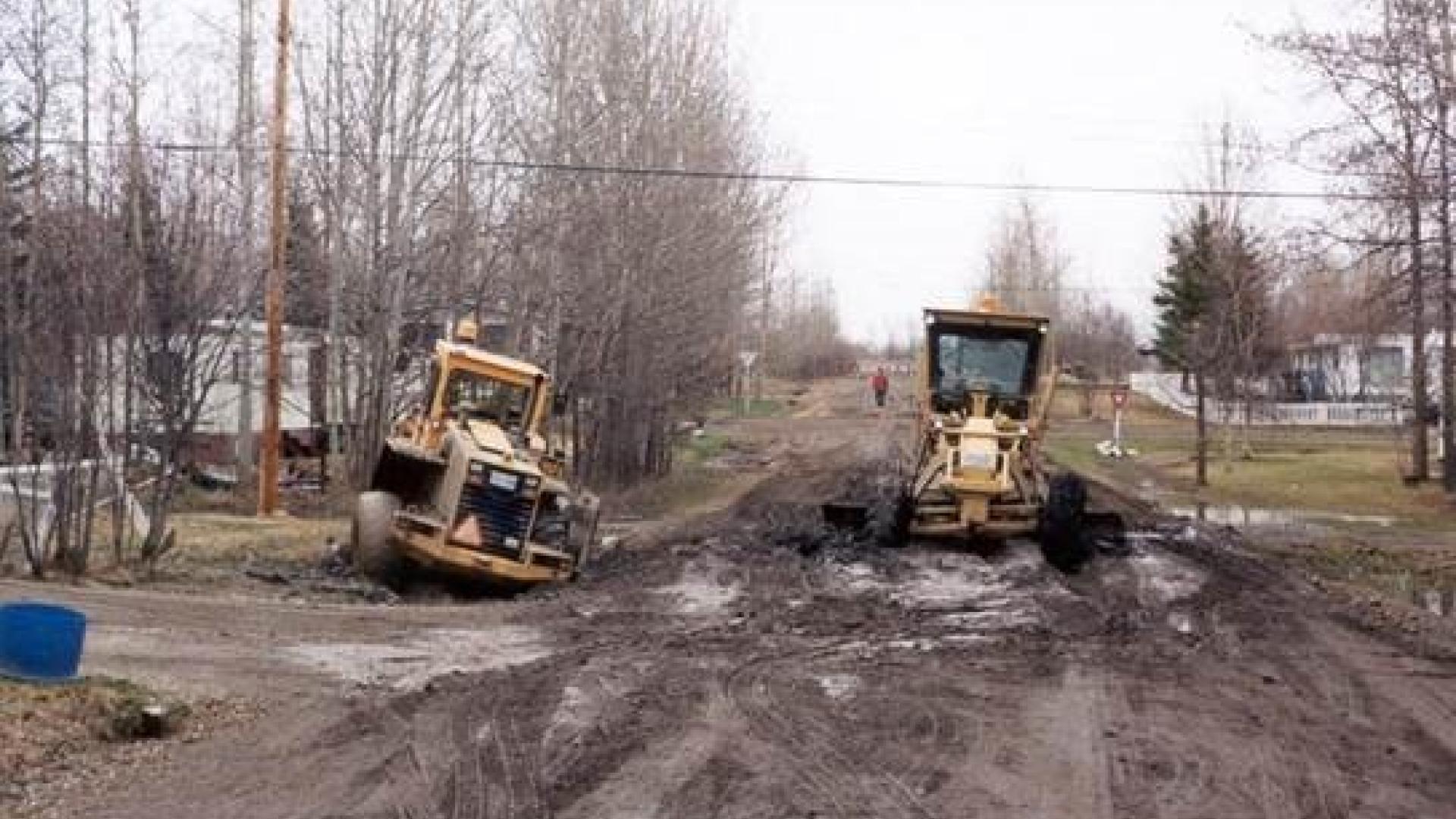 A grader is stuck on a city gravel road during spring break up.