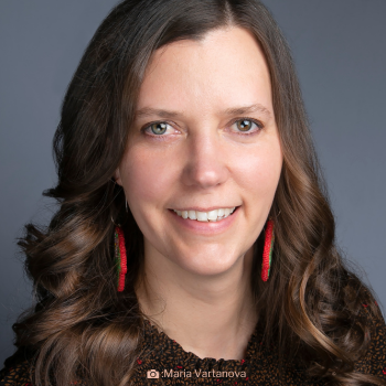 Headshot of Catherine Ruddell. There is a smiling woman with long brown hair and red earings.