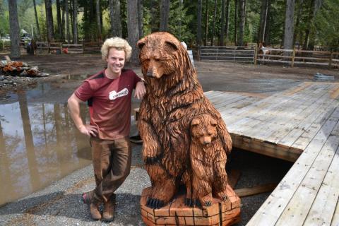 Ryan Cook stands beside a bear carving.