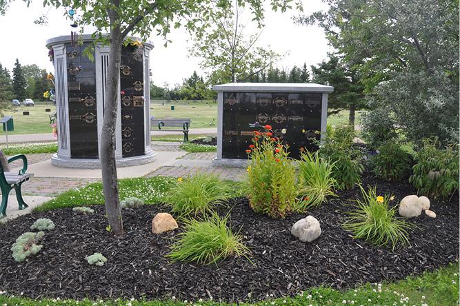 Cemetery memorial headstones near a park bench.
