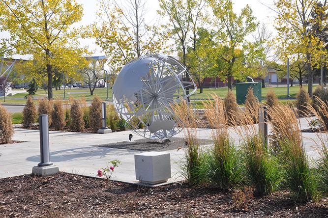 Structure of globe made out of metal in the middle of a park.